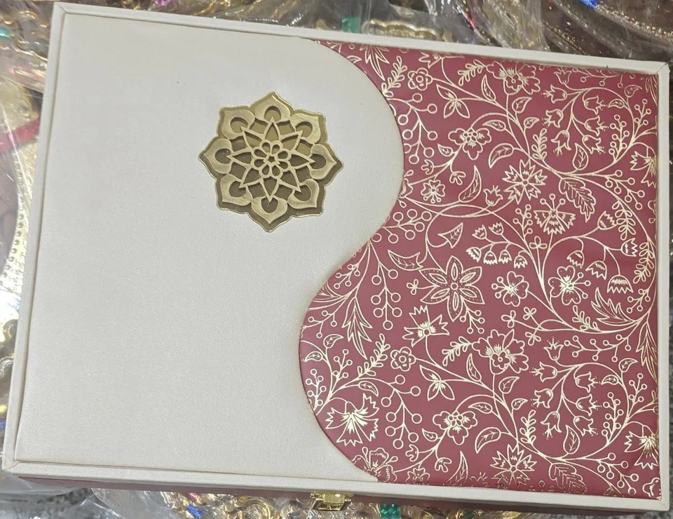 A cream box with a rose panel printed with gold flowers, and a brass-tone flower motif on the lid