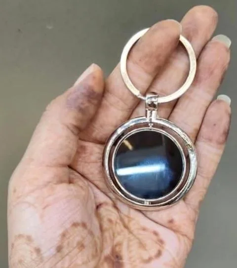 Round keychain with a black disc in a silver-tone ring
