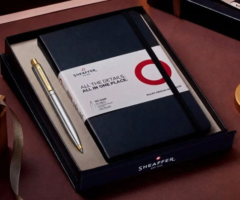 Sheaffer Sentinel 333 ballpoint with a brushed chrome barrel and gold-tone trim, with a black ruled medium notebook, in a…